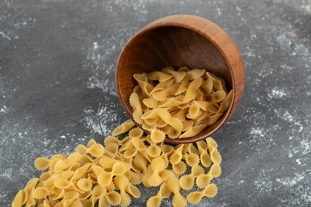 Macarrones tonde farfalle seco crudo sobre una mesa de mármol.