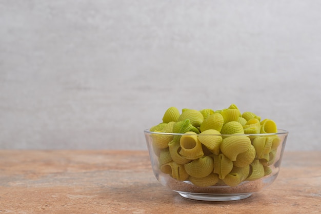 Macarrones verdes sin preparar en placa de vidrio sobre fondo de mármol. Foto de alta calidad