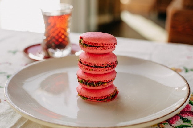 maccherones rosados dulces y redondos dentro de un plato blanco junto con té caliente durante el día