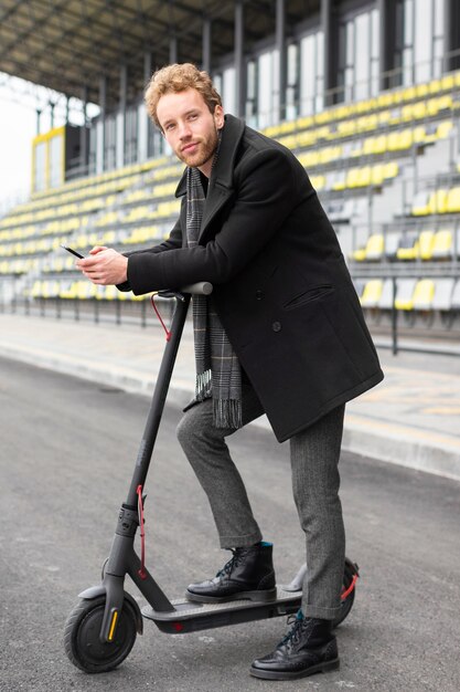 Macho adulto posando con su scooter eléctrico