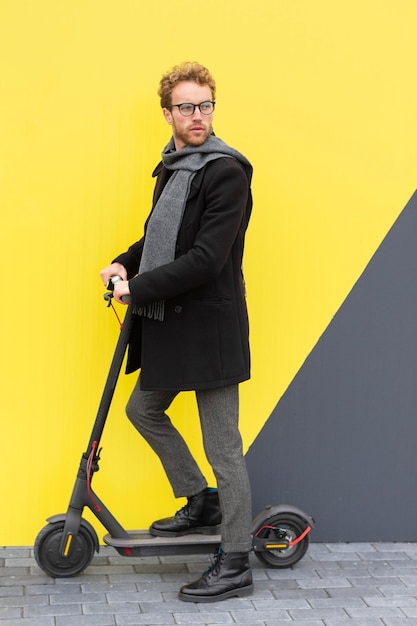 Macho adulto posando con su scooter eléctrico