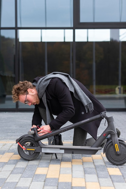 Foto gratuita macho adulto reparando su scooter eléctrico