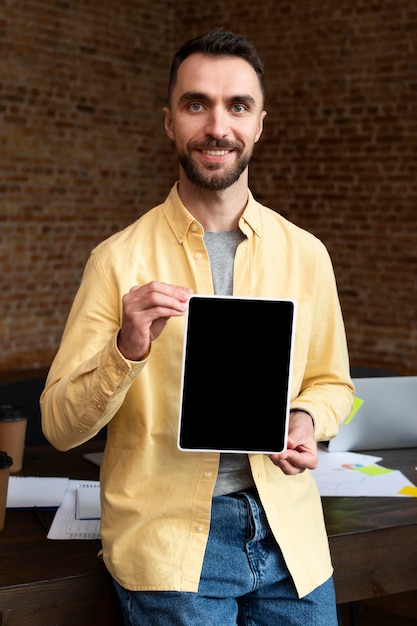 Foto gratuita macho adulto sosteniendo una tableta en la oficina