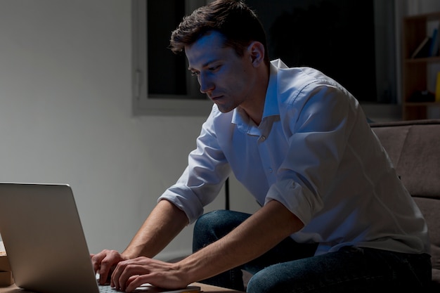 Macho adulto trabajando en la computadora portátil en la noche