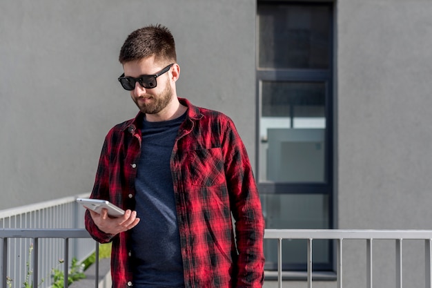 Foto gratuita macho adulto usando tableta afuera en la ciudad