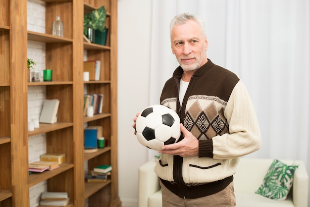 Foto gratuita macho envejecido con pelota cerca de estanterías en habitación