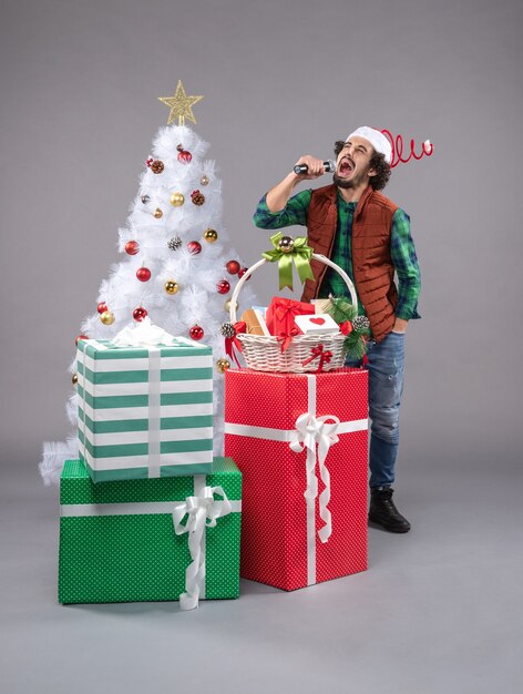 macho joven alrededor de diferentes regalos en gris