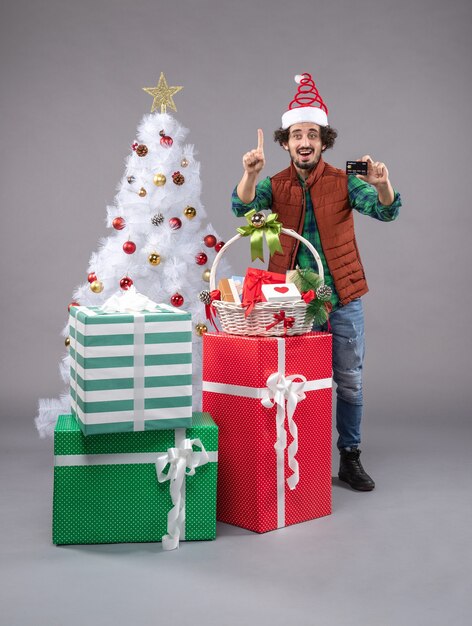 macho joven alrededor de regalos de navidad en gris