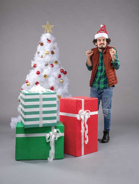 macho joven alrededor de regalos de navidad en la luz