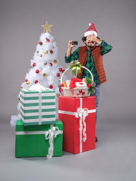 macho joven alrededor de regalos de vacaciones en gris