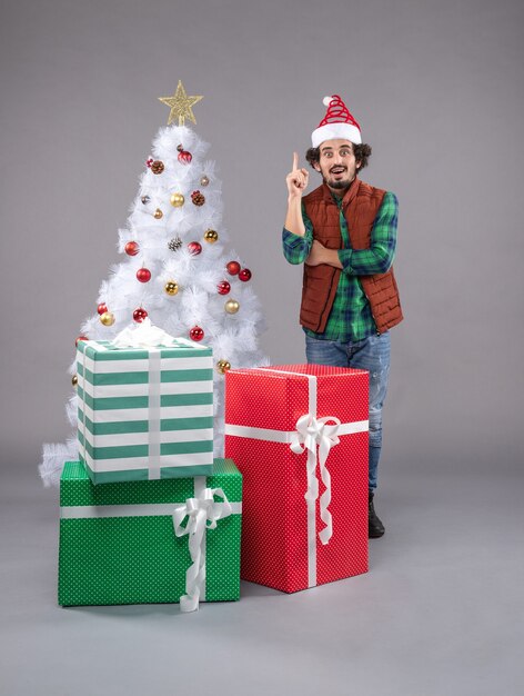 macho joven alrededor de regalos de vacaciones en gris