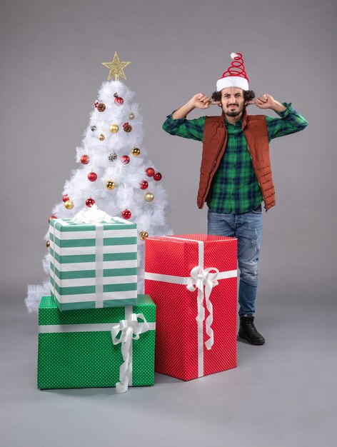 macho joven alrededor de regalos de vacaciones en gris