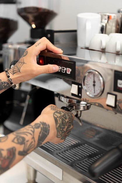 Macho joven barista con tatuajes con la máquina de café en el trabajo