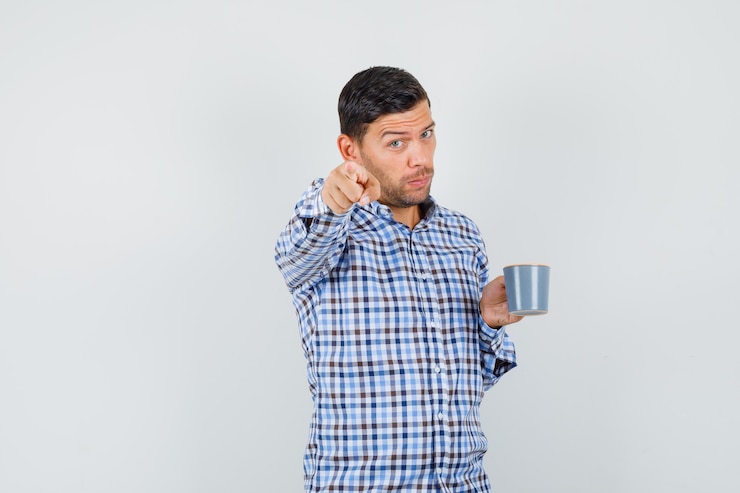 Foto gratuito macho joven en camisa a cuadros sosteniendo una taza de bebida