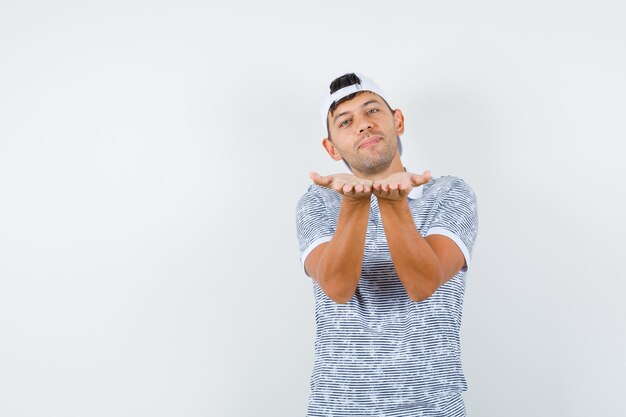 Foto gratuita macho joven enviando beso soplado en camiseta y gorra y mirando alegre