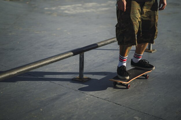 Macho joven haciendo diferentes trucos con una patineta en el parque