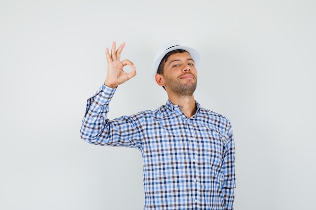 Macho joven mostrando gesto ok en camisa a cuadros