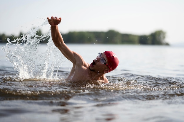 Macho joven nadando en el lago