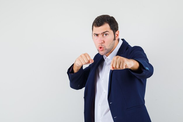 Macho joven de pie en pose de lucha en camisa