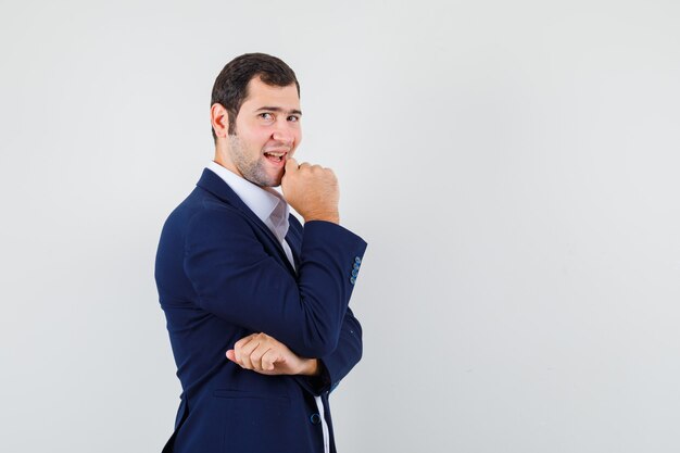 Macho joven de pie en pose de pensamiento en camisa