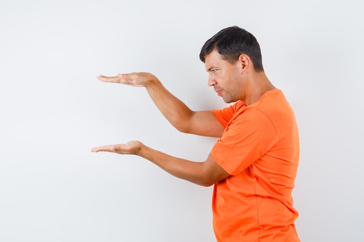 Foto gratuito macho joven que muestra el signo de tamaño en camiseta naranja y parece sensato