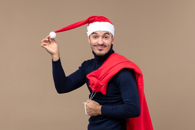 Macho joven de vista frontal con bolsa actual y gorra, vacaciones de navidad santa