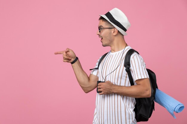 Macho joven de vista frontal en camiseta blanca con binoculares en el fondo de color rosa