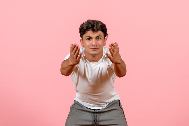 Macho joven de vista frontal en camiseta blanca sobre fondo rosa