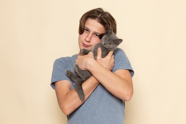 Un macho joven de vista frontal en camiseta gris con lindo gatito gris