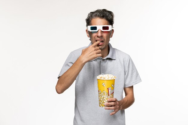 Macho joven de vista frontal comiendo palomitas de maíz en gafas de sol d en escritorio blanco