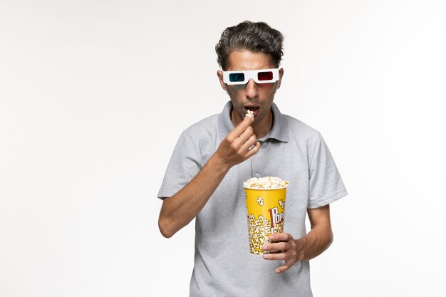 Macho joven de vista frontal comiendo palomitas de maíz en gafas de sol d sobre superficie blanca