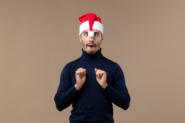 Macho joven de vista frontal con gorro rojo de Navidad en Navidad de vacaciones de escritorio marrón