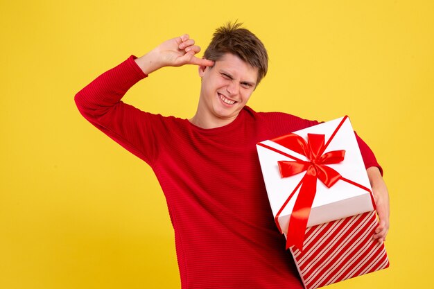 Macho joven de vista frontal con gran Navidad presente sobre fondo amarillo