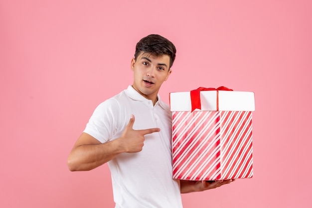 Foto gratuita macho joven de vista frontal con gran regalo de navidad sobre fondo rosa