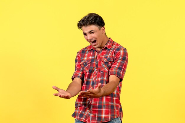 Macho joven de vista frontal gritando en camisa brillante sobre fondo amarillo