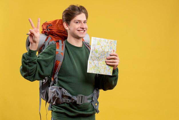 Macho joven de vista frontal con mochila sosteniendo mapa