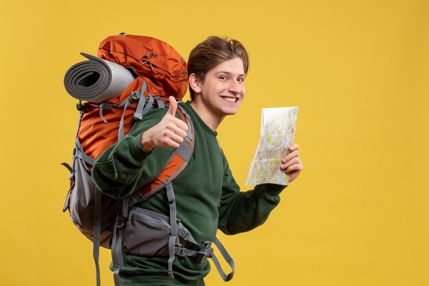 Macho joven de vista frontal con mochila sosteniendo mapa