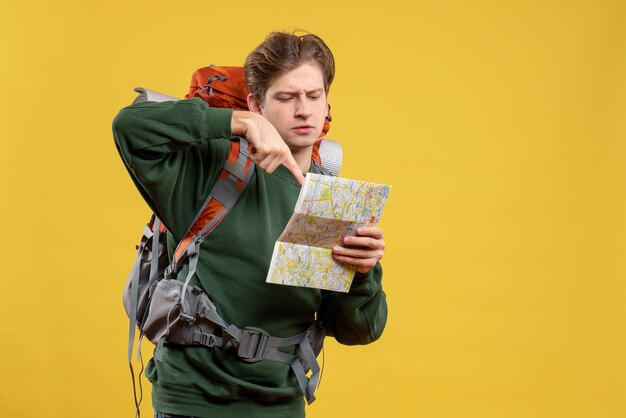 Macho joven de vista frontal con mochila sosteniendo mapa