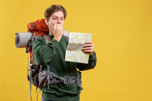 Macho joven de vista frontal con mochila sosteniendo mapa