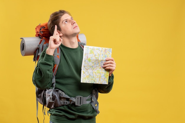 Macho joven de vista frontal con mochila sosteniendo mapa
