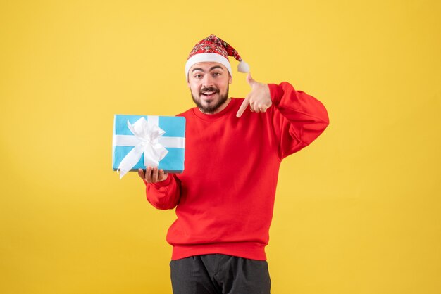 Macho joven de vista frontal con Navidad presente sobre fondo amarillo