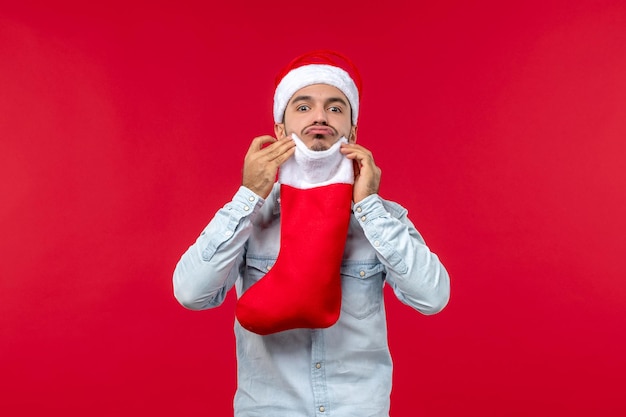 Macho joven de vista frontal sosteniendo un calcetín de Navidad, vacaciones de Navidad