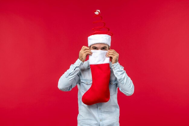 Macho joven de vista frontal sosteniendo un calcetín de Navidad, vacaciones de Navidad