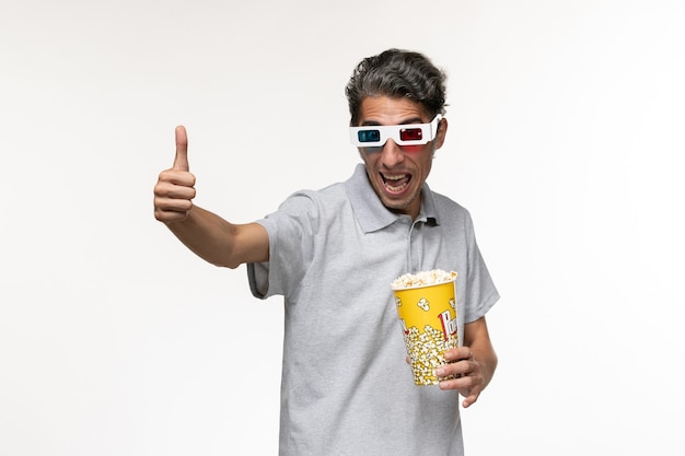 Macho joven de vista frontal sosteniendo palomitas de maíz en gafas de sol d sobre superficie blanca