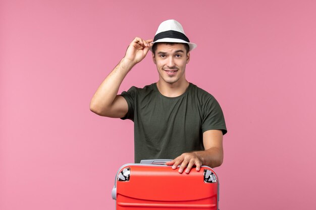 Macho joven de vista frontal en vacaciones con bolsa roja en el espacio rosa