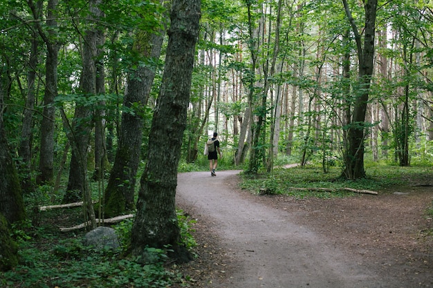 Macho con una mochila caminando por un sendero en medio del bosque