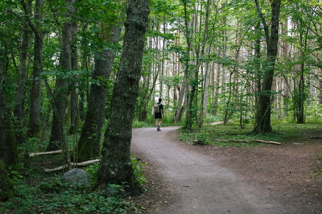 Macho con una mochila caminando por un sendero en medio del bosque