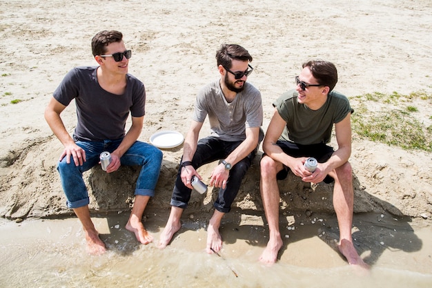 Foto gratuita machos descalzos charlando en la playa de arena