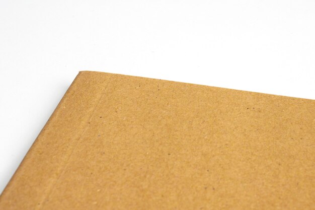 Macro de la esquina del cuaderno en blanco con tapa dura de cartón aislado en blanco