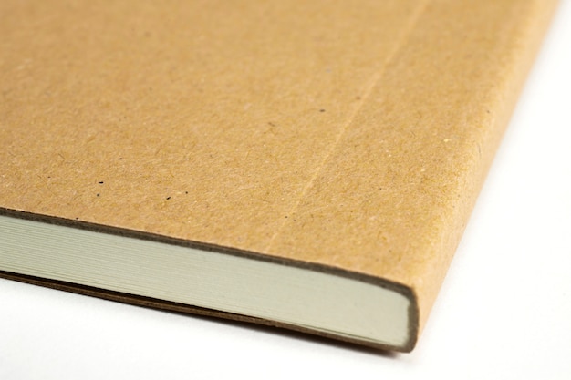 Macro de la esquina del cuaderno en blanco con tapa dura de cartón aislado en blanco